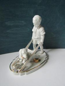 Porcelánová soška chlapec veze jezevčíka na kolečku 