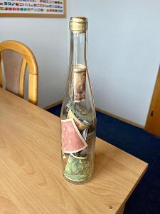 Skleněná lahev se starými bankovkami